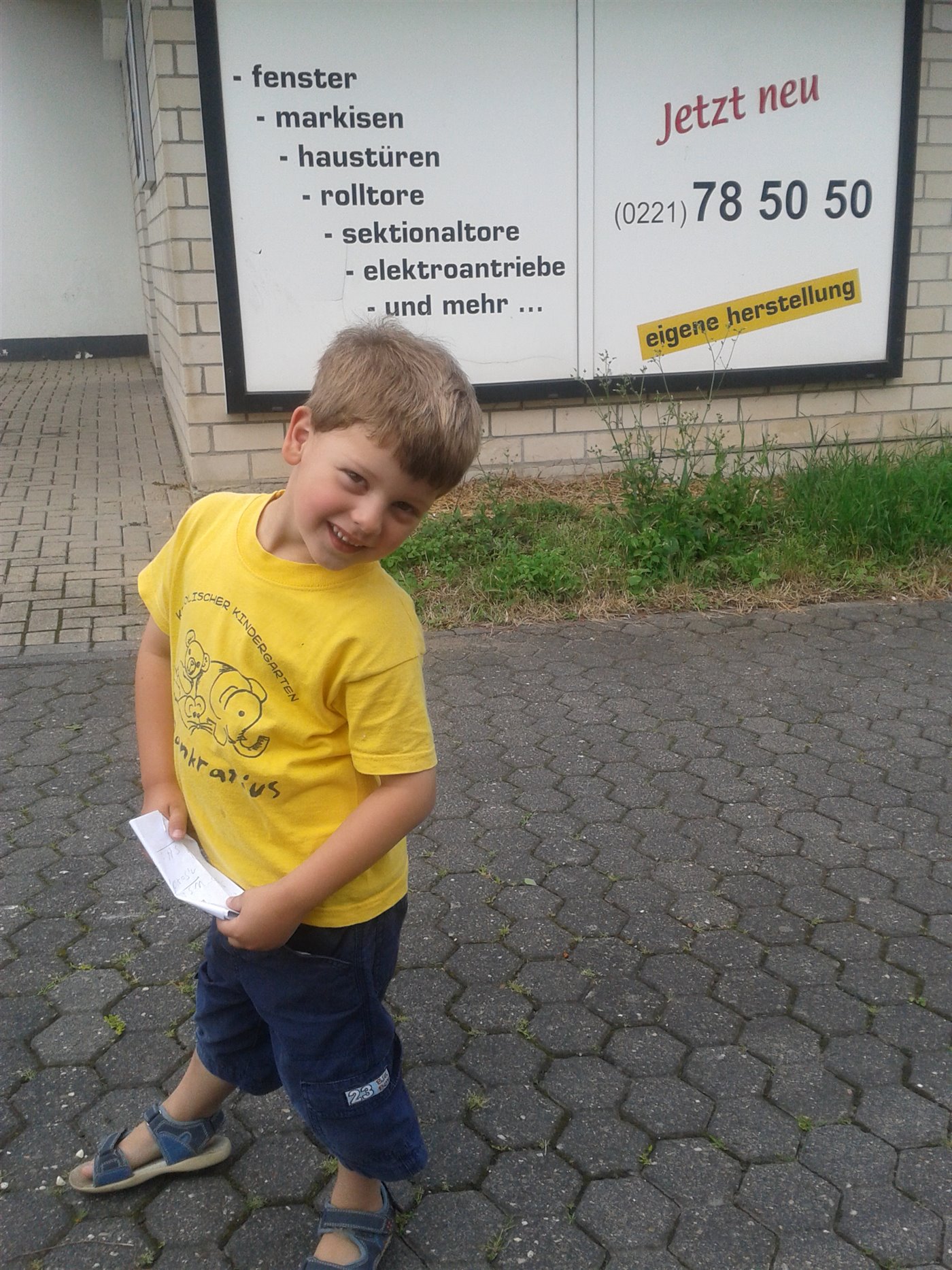 Kind vor der alten Rolladen-Hohn-Werbetafel mit dem Leistungsangebot