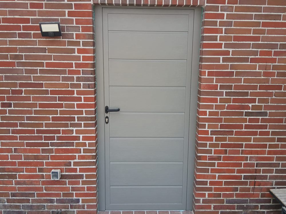 Neue graue Nebeneingangstür in einer Klinkerfassade